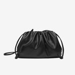 De Serena Zachte Leren Pouch Tas van Liora The Label heeft een minimalistisch ontwerp in zwart boterzacht leer, met een gathered top en dunne schouderband, stijlvol getoond op een witte achtergrond.