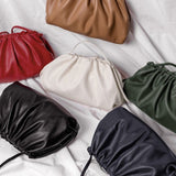 Zes Serena Zachte Leren Pouch Tassen van Liora The Label in bruin, rood, wit, groen, zwart en marineblauw worden getoond op witte stof - elk met een gerimpelde bovenkant en botersoepel leer voor een moderne, luxe uitstraling.