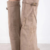 Een persoon draagt Liora The Label Dames Kniehoog Laarzen met Brede Flare Bovenkant en Blokhak, staande op een licht houten vloer tegen een witte achtergrond.