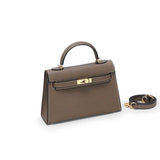 De Liora The Label Aurora Signature Mini Leren Handtas is een bruine gestructureerde handtas met bovenhandgreep en witte stiksels, gouden hardware en wordt geleverd met een afneembare schouderriem.