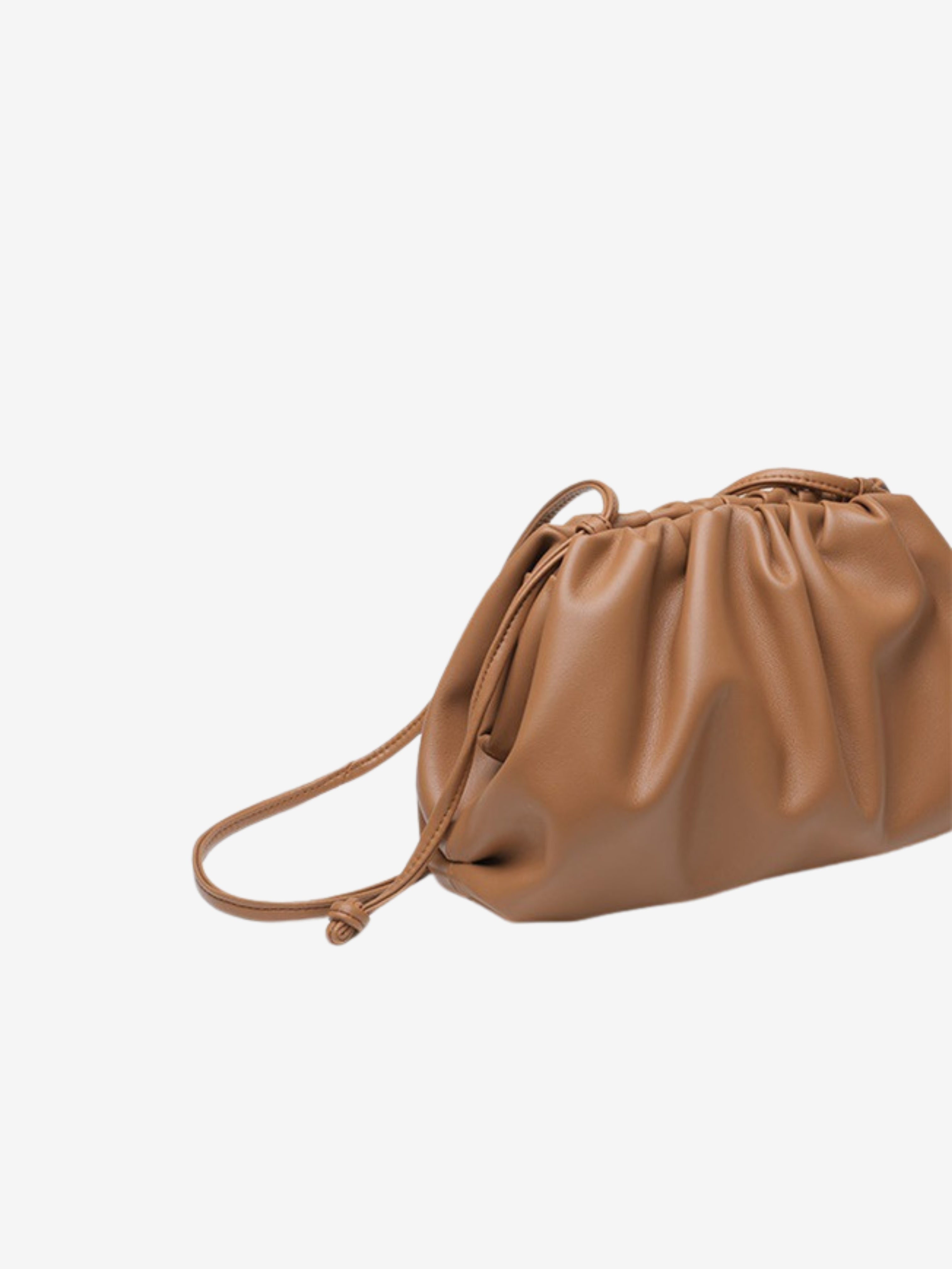 De Serena Zachte Leren Pouch Tas van Liora The Label is een bruine, geruwde leren schoudertas met een lange dunne riem en een minimalistisch ontwerp, afgebeeld tegen een witte achtergrond.