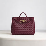 De Alyn Zwarte Geweven Midi Leren Tote Bag van Liora The Label heeft een ontwerp van geweven leer, een handvat aan de bovenkant en een gouden gesp, luxe weergegeven op een wit oppervlak met een effen lichte achtergrond.