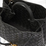 Een close-up van de Alyn Zwarte Geweven Midi Leren Tote Bag van Liora The Label, met gouden hardware en gevlochten hengsels. Deze elegante handtas dames rust op een wit oppervlak, wat de tijdloze uitstraling benadrukt.