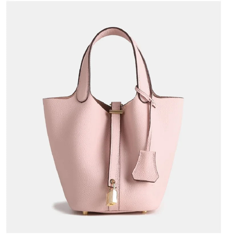 De Elaris | Luxe Taupe Leren Emmer Tas van Liora The Label is een eersteklas tote bag met een gestructureerde vorm, goudkleurige details, glad kiezelleer, hangende slotbedel en kort handvat - elegant en tijdloos in ontwerp.