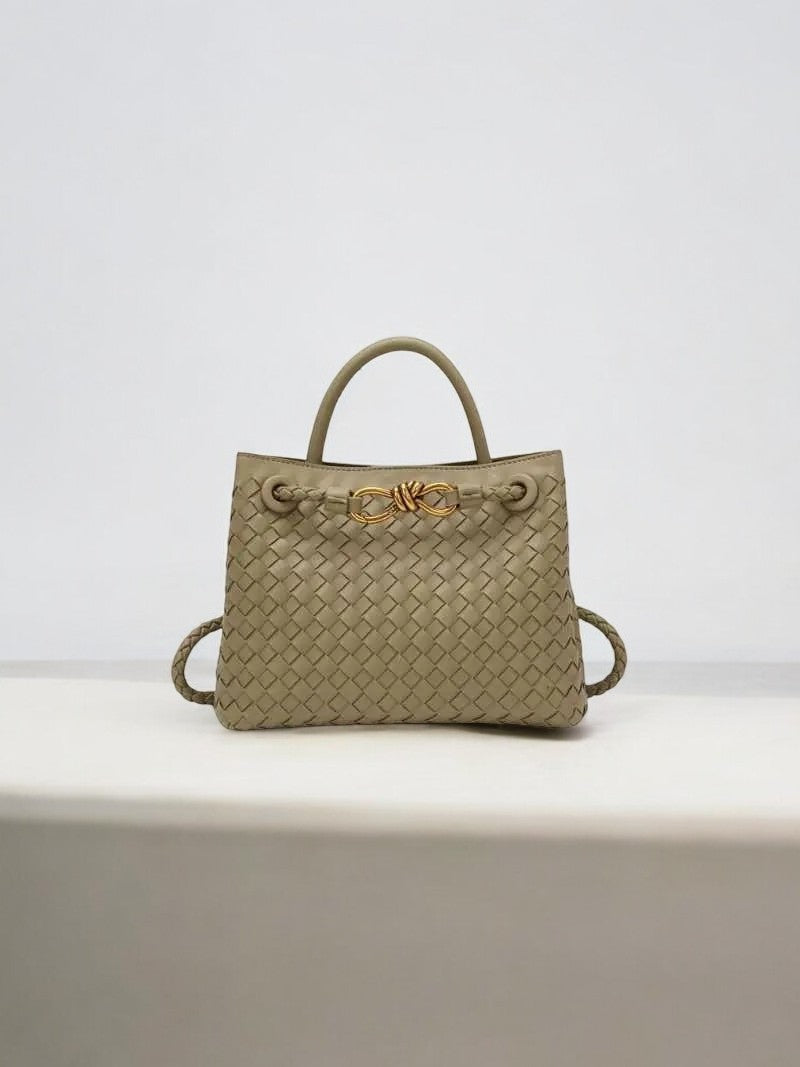 De Alyn Zwarte Geweven Midi Leren Tote Bag van Liora The Label heeft twee bovenhengsels, goudkleurige hardware en een gestructureerd silhouet, elegant gepresenteerd tegen een effen lichte achtergrond.