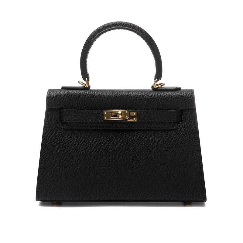 De Galatea handtas van Liora The Label is een elegante, zwarte vegan leren tas met saffiano-textuur, top handvat, goudkleurige details en een draaivergrendeling. Een klassieke mix van luxe en functionaliteit.