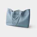 De Emma Zwarte Leren Tote Bag van Liora The Label is een klassieke, veelzijdige handtas met twee hengsels en een minimalistisch design, gepresenteerd op een effen witte achtergrond.