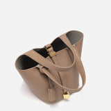 De Elaris Luxe Taupe Leren Emmer Tas van Liora The Label is gemaakt van eersteklas leer met goudkleurige hardware, een klein hangslot, dubbele handgrepen en een gestructureerd open ontwerp - tijdloze elegantie tegen een witte achtergrond.