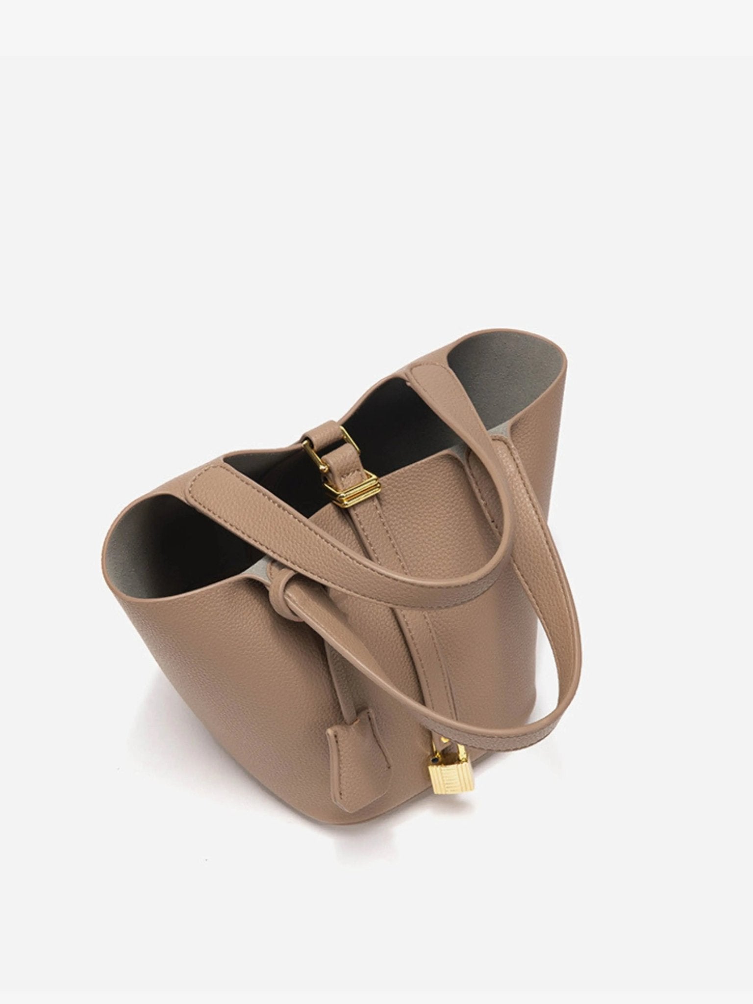 De Elaris Luxe Taupe Leren Emmer Tas van Liora The Label is gemaakt van eersteklas leer met goudkleurige hardware, een klein hangslot, dubbele handgrepen en een gestructureerd open ontwerp - tijdloze elegantie tegen een witte achtergrond.