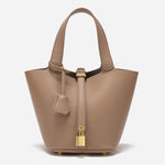 De Elaris Luxe Taupe Leren Emmer Tas van Liora The Label is een tijdloze, elegante bucket bag met gestructureerd leer, dubbele hengsels, een centrale riem met goudkleurig hangslot en een leren sleuteletui - de minimalistische stijl maakt een opvallend statement.
