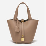 De Elaris Luxe Taupe Leren Emmer Tas van Liora The Label is een tijdloze, elegante bucket bag met gestructureerd leer, dubbele hengsels, een centrale riem met goudkleurig hangslot en een leren sleuteletui - de minimalistische stijl maakt een opvallend statement.