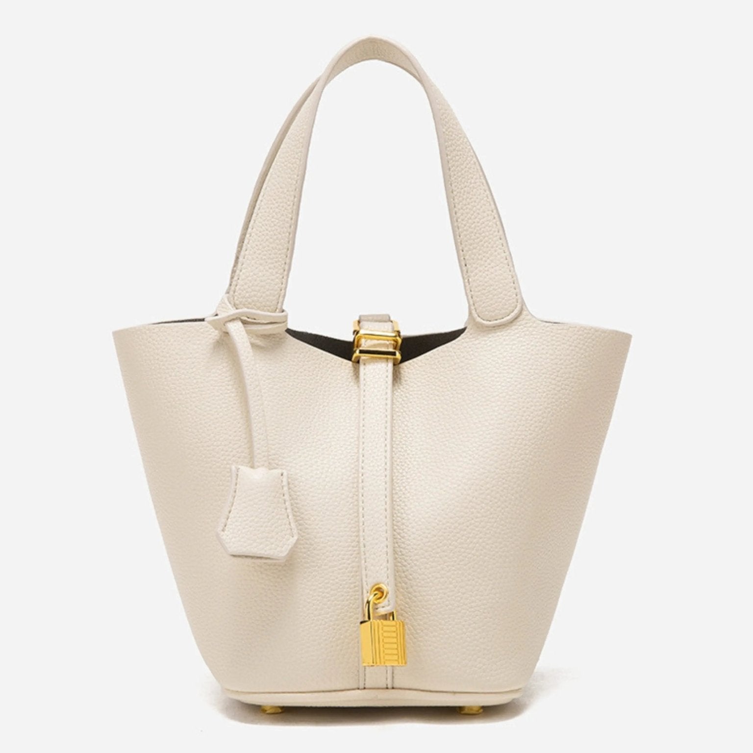 De Elaris Luxe Taupe Leren Emmer Tas van Liora The Label is een eersteklas, crèmekleurige bucket bag met twee bovenhengsels en een gouden hangslotdetail, afgebeeld tegen een effen witte achtergrond.