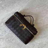 De Luxe Geweven Box Bag van Liora The Label is een elegante donkerbruine crossbody met gouden ritssluiting, getoond op een licht getextureerd oppervlak.