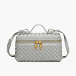 De Luxe Geweven Box Bag van Liora The Label is een kleine, rechthoekige, donkerbruine crossbody van veganistisch leer met gouden ritssluiting, gouden hardware, handvat aan de bovenkant en verstelbare schouderriem.