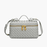 De Luxe Geweven Box Bag van Liora The Label is een kleine, rechthoekige, donkerbruine crossbody van veganistisch leer met gouden ritssluiting, gouden hardware, handvat aan de bovenkant en verstelbare schouderriem.