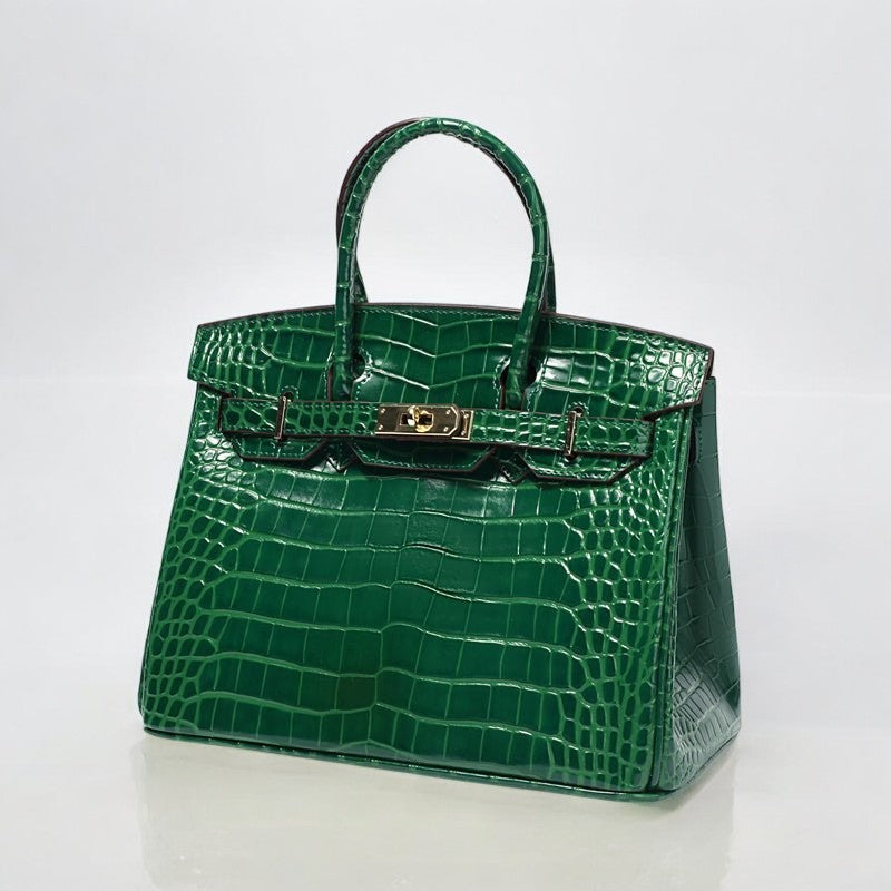 De Isla Luxe Smaragdgroene Crocodilleer Geëmbossede Tote Bag van Liora The Label is een veganistische leren handtas met krokostructuur, dubbele handvatten en gouden sluiting, schitterend gepresenteerd tegen een witte achtergrond.